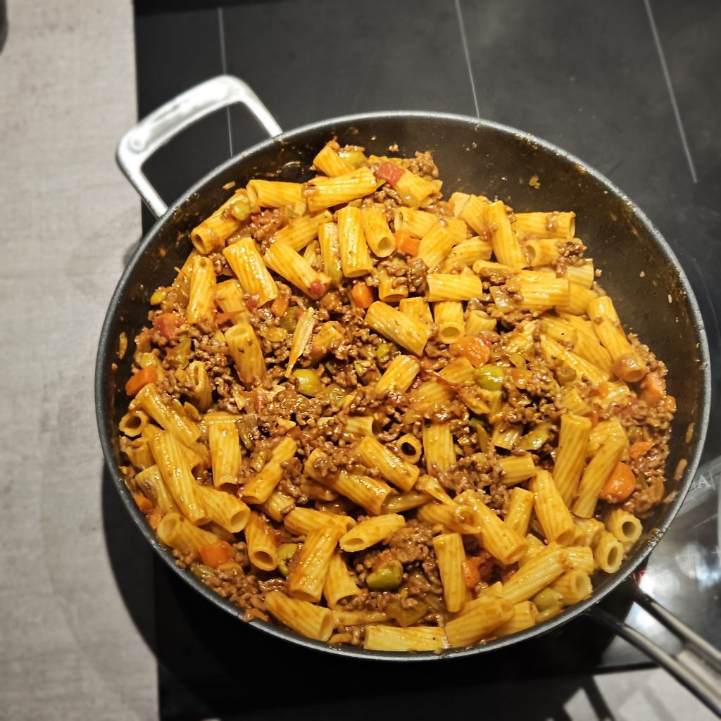 Finished beef ragù with green olives simmering in pan
