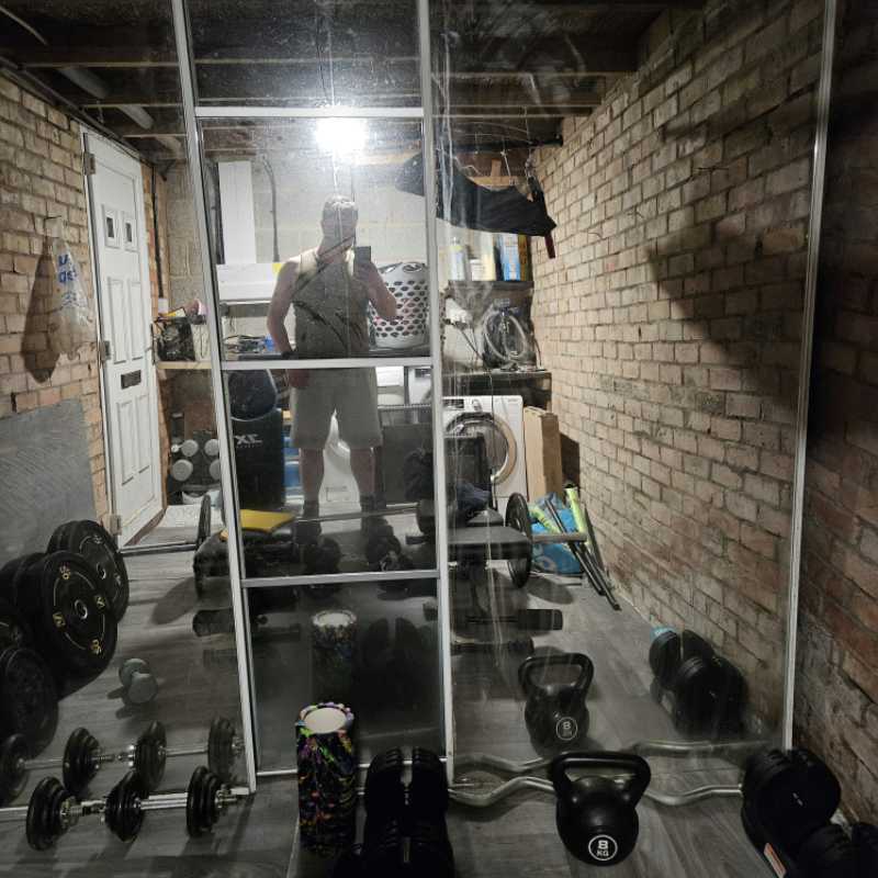 Garage gym with dumbbells, kettlebells, barbell, bench, and punch bag used for post-hernia surgery rehabilitation training